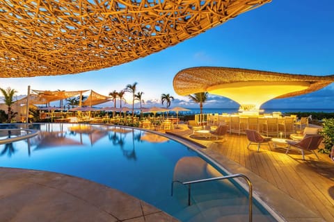 Sip and sparkle beside the sculptural bar over calm water.