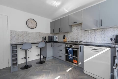 Modern and fully equipped kitchen with sleek grey cabinetry, bar seating, and everything you need to cook and dine in style.