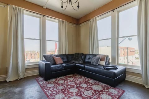 Sunlit corner living room with panoramic downtown views and cozy, modern seating.