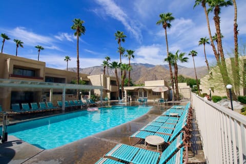 Unwind at the resort pool surrounded by palm trees and mountains, with access to a shared hot tub and relaxing outdoor amenities.