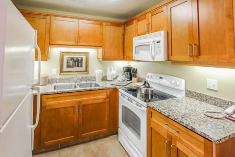 This fully equipped kitchen showcases modern wooden cabinetry and stylish countertops, ideal for preparing meals during your stay in the heart of Palm Springs.