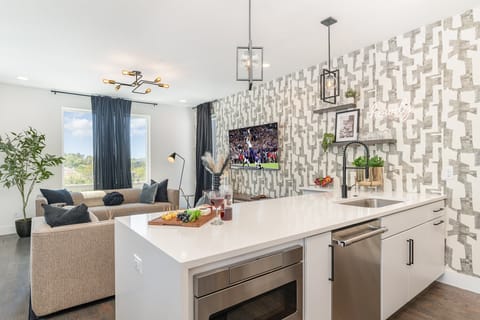 2nd Floor: Sleek and stylish kitchen boasting a bold accent wall, gleaming countertops, and stainless appliances.