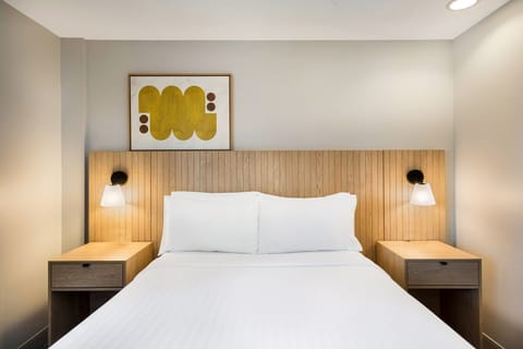 Drift off in a calm, cozy bed with glowing sconces.
