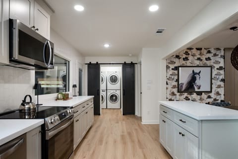 View of the large kitchen and of the large laundry room with 2 sets of washer and dryers