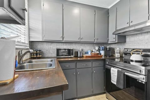 The kitchen blends style and function with its warm wood countertops, modern appliances, and cozy charm.