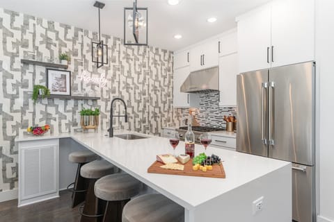 Unit 2: Sleek and stylish kitchen boasting a bold accent wall, gleaming countertops, and stainless appliances. (2nd Floor)