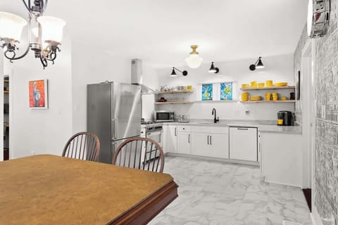 Open dining and kitchen space with marble-style floors, stainless appliances, and stained-glass accents. Enjoy meals at a vintage table and cook with ease in this bright, fully equipped kitchen.