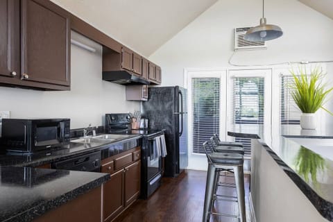 Modern kitchen with dark cabinets, black appliances, and bar seating for casual dining.