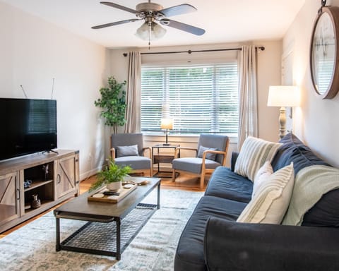 Bright and cozy living room with natural light, a smart TV, and plush seating—perfect for relaxing after a day out.