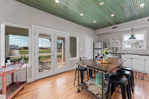 Gather around the island as golden-hour light filters through the French doors. It’s where food meets conversation, all framed by the colors of the Texas evening sky just beyond.