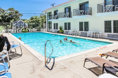 Families relax in the spacious outdoor pool area, complete with lounge chairs and sunny skies, ideal for quality time.