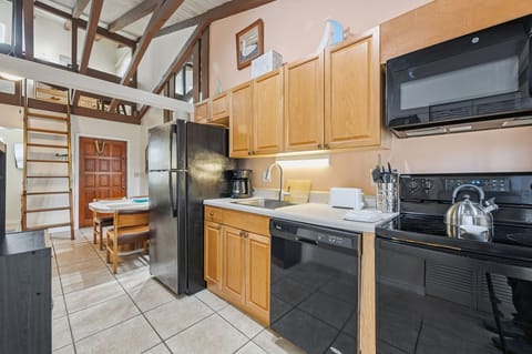 A closer look at the kitchen highlights modern appliances and wood cabinetry beneath the lofted sleeping area.