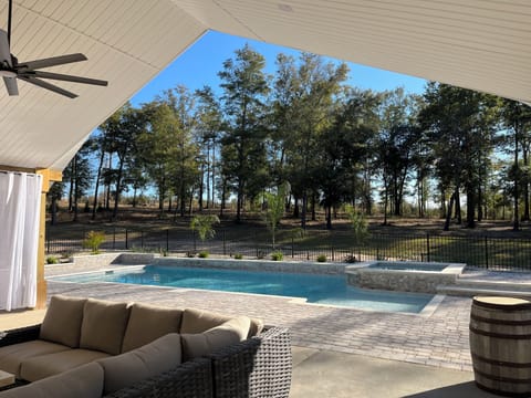 Backyard covered space with seating, pool and hot tub