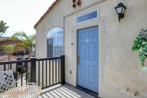 This charming second-floor entry features a soft blue door opening onto a private balcony, perfect for a morning coffee in a tranquil coastal setting.