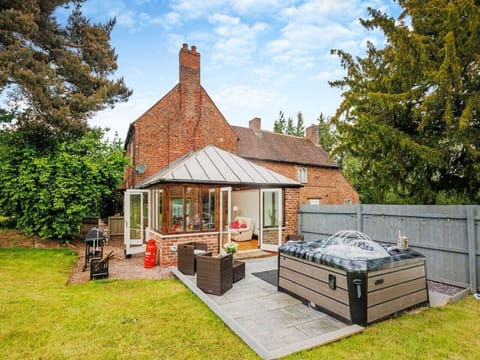 Sunlit patio with bubbling hot tub beside the conservatory