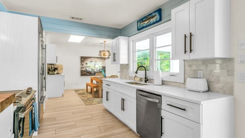 The fully stocked kitchen boasts a Sub-Zero fridge and acacia wood butcher block counters. A peninsula with seating provides the perfect spot for casual meals or morning coffee.