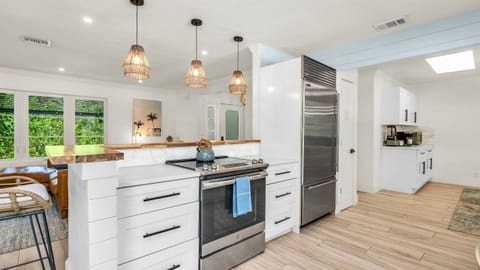 The fully stocked kitchen boasts a Sub-Zero fridge and acacia wood butcher block counters. A peninsula with seating provides the perfect spot for casual meals or morning coffee.