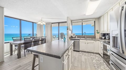Bright, beach-view kitchen with stainless appliances, large island, and panoramic Gulf views—open to a spacious dining area for easy coastal living.