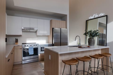 Stylish and functional tall ceiling kitchen with stainless steel appliances, full size mirror and natural wood accents.