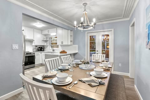Dining room area with double doors to patio. View of kitchen on the left and the Den and Main Bedroom 1 on the right.