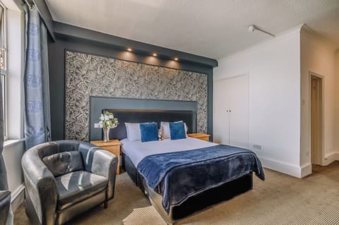 Lounge in luxury with statement wallpaper and a deep, comfy bed.