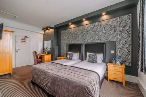 Settle into twin comfort beneath warm lighting and patterned feature wall