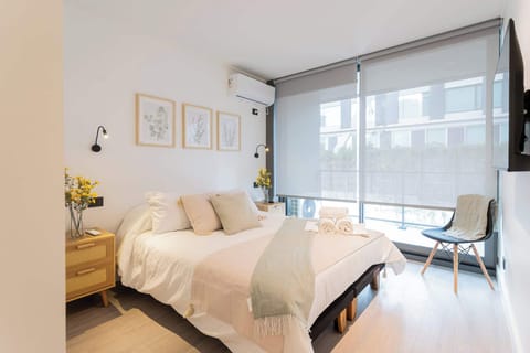 Relax in this bright and cozy bedroom with modern decor and abundant natural light, perfect for a restful stay.