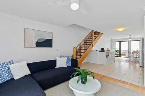 Open-plan living area with ceiling fan, comfortable lounge seating, 55” Smart TV