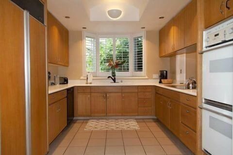Cook up paradise in this spacious, sunlit kitchen framed by garden views and warm wood finishes.
