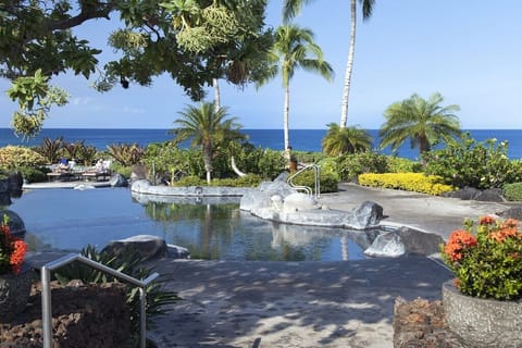 Swim beside lava rock, lush foliage, and the Pacific, surrounded by colorful blooms and swaying palms.

