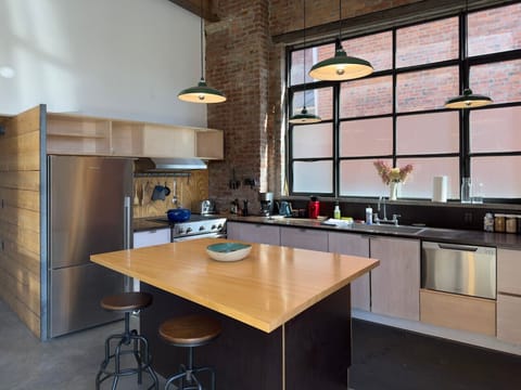 Modern kitchen with an oversized island, bar seating, and striking industrial windows.