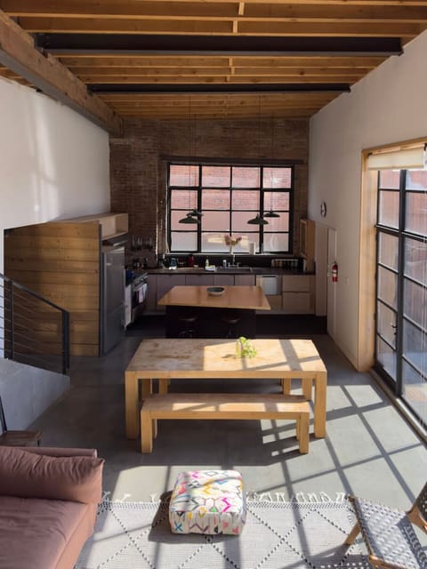 Expansive, sunlit living and dining area with industrial-style windows and warm wood accents.