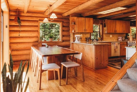 A live edge wood dining table set up for 10 guests with 2 extra chairs to seat up to 12. A Stokke high chair is also stored in the laundry room.