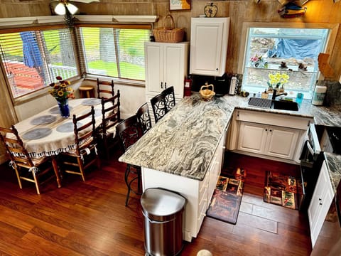Bright kitchen with granite counters, bar seating, and forest-view dining.