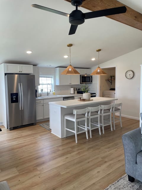 New kitchen with large island, stainless steel appliances and farmhouse sink
