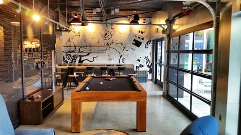 Challenge friends to a pool match beside sunlit glass doors.