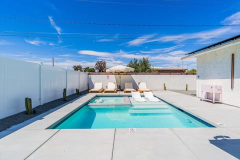 Sun-soaked pool w/ privacy fencing, loungers, & a mountain backdrop—perfect for cooling off or all-day relaxing.
