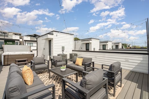 3rd Unit (4th Floor): Private rooftop deck with hot tub, outdoor seating, bistro lighting, and stunning city skyline views.