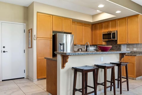 Modern kitchen with granite countertops and breakfast bar seating for three.