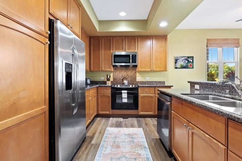 Spacious kitchen boasts granite tops, full cookware, bright lighting, and scenic dining area views.

