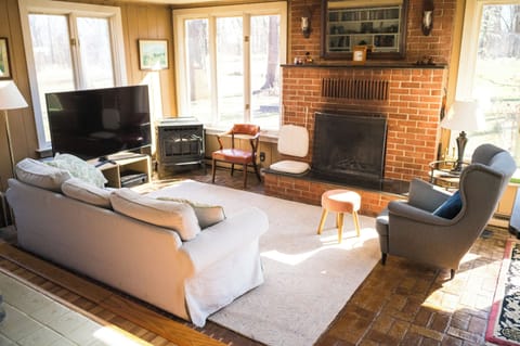 Cozy living room with 65-inch TV, wood burning fireplace and large windows