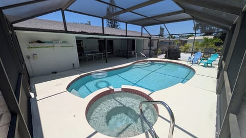 Enclosed heated pool and spa in backyard with table tennis, dining table, TV