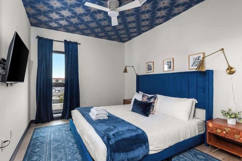 The Rayleigh 2nd Bedroom:  King-size bed with designer furnishings, smart TV, and unattached bathroom. Bathroom includes dual vanities, a walk-in closet, and a shower.