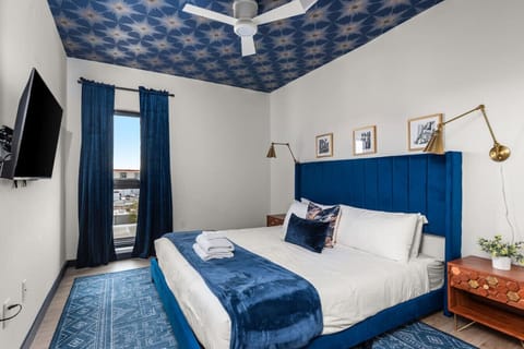 The Rayleigh 2nd Bedroom:  King-size bed with designer furnishings, smart TV, and unattached bathroom. Bathroom includes dual vanities, a walk-in closet, and a shower.