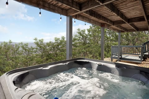 Relax in the covered hot tub with views of the surrounding trees and hills.