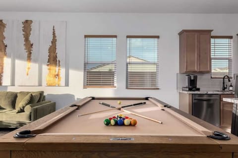 Relax in the spacious living room with plush seating, a smart TV, and a sleek pool table that doubles as a dining table, perfect for both game nights and enjoying a nice meal. 