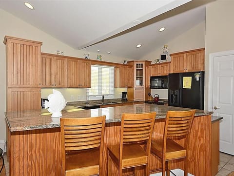 Culinary delights await in this gourmet kitchen, featuring elegant granite countertops, custom cabinetry, and a convenient breakfast bar, perfect for casual meals while soaking in the sunlit ambiance.