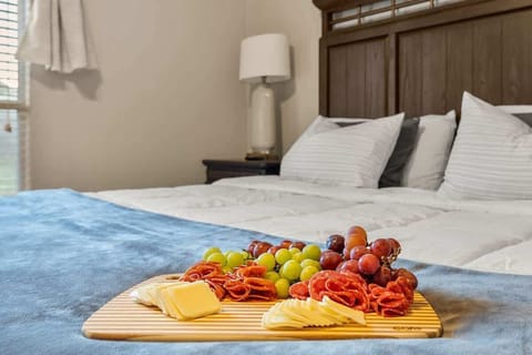 Indulge in comfort and style in the master bedroom, featuring a luxurious king-sized bed and a beautifully arranged charcuterie board, perfect for a relaxing night in your Killeen short-term rental.