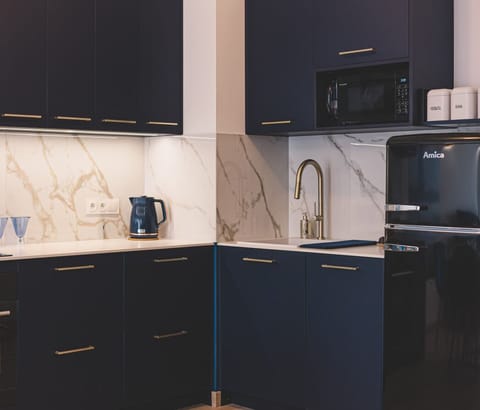 Deep blue cabinetry with gold handles – elegance meets function in this stylish coastal apartment.
