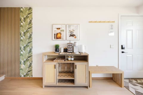 A curated coffee nook with wooden shelves, thriving plants, and "slow" wall art—a tranquil reminder to savor life’s simple moments in this zen-inspired corner.